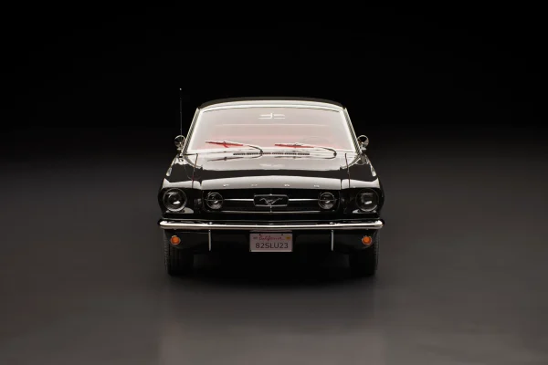 Front view 3D render of a black classic Ford Mustang fastback on a dark studio floor, license plate 82SLU23